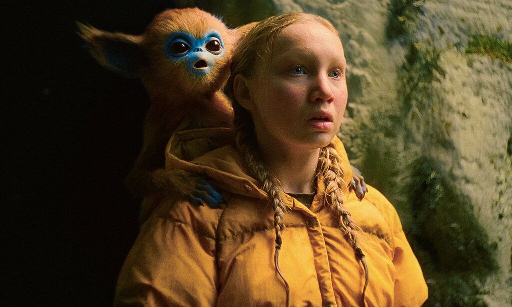 ein Mädchen steht vor einer Felswand und guckt erstaunt, hinter ihr ist ein Ochi und guckt genauso erstaunt