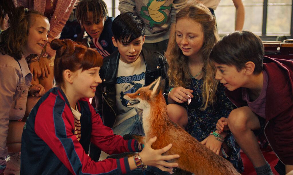 einige Schulkinder hocken beieinander, in ihrer Mitte ein Fuchs