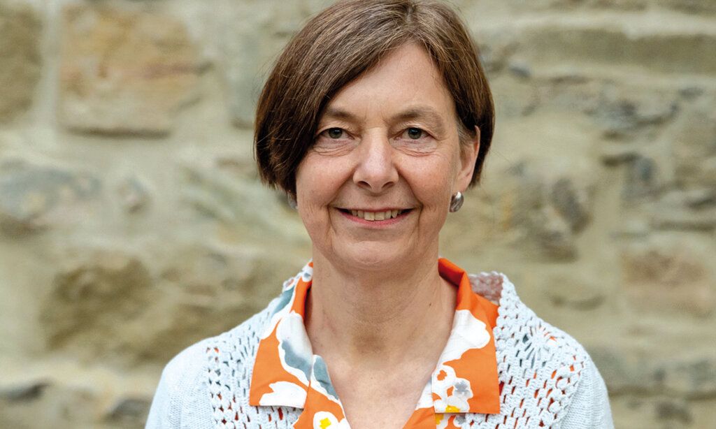 Porträt von Dr. Elisabeth Müller, im Hintergrund Steinmauer