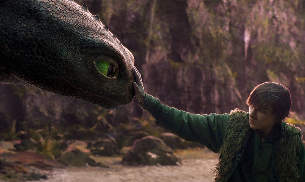 Filmszene Drachenzähmen leicht gemacht, junger Mann streichelt den Kopfeines Drachen