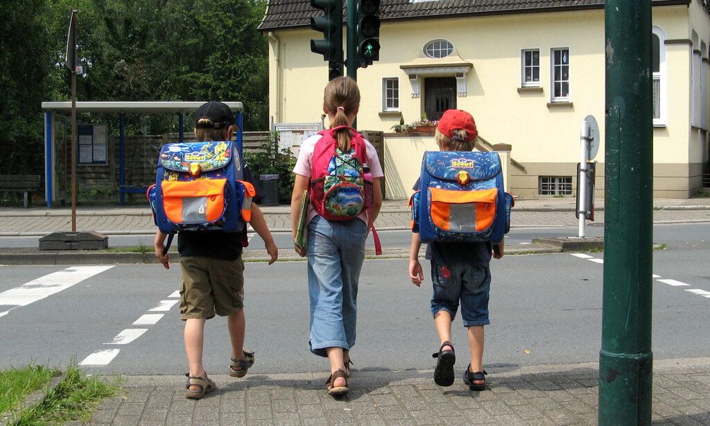 Drei Schulanfänger am Straßenüberweg