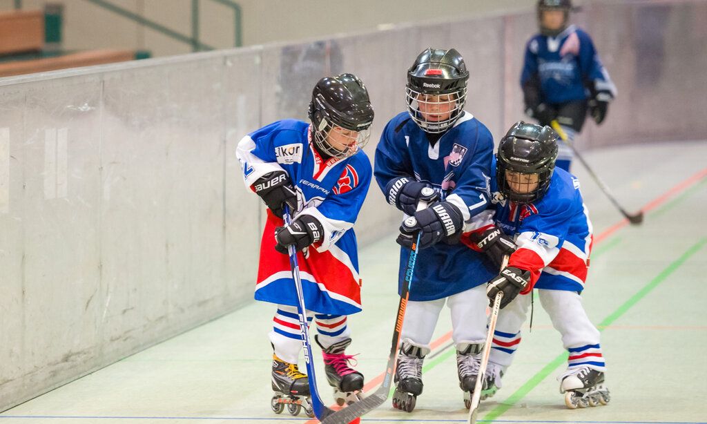 Drei Kinder spielen Inlineskate-Hockey