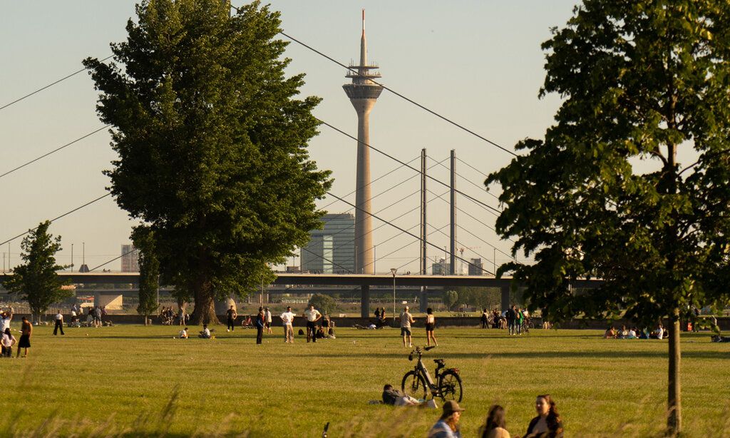 Leute auf der Düsseldorfer Rheinwiese, im Hintergrund Kniebrücke und Fernsehturm
