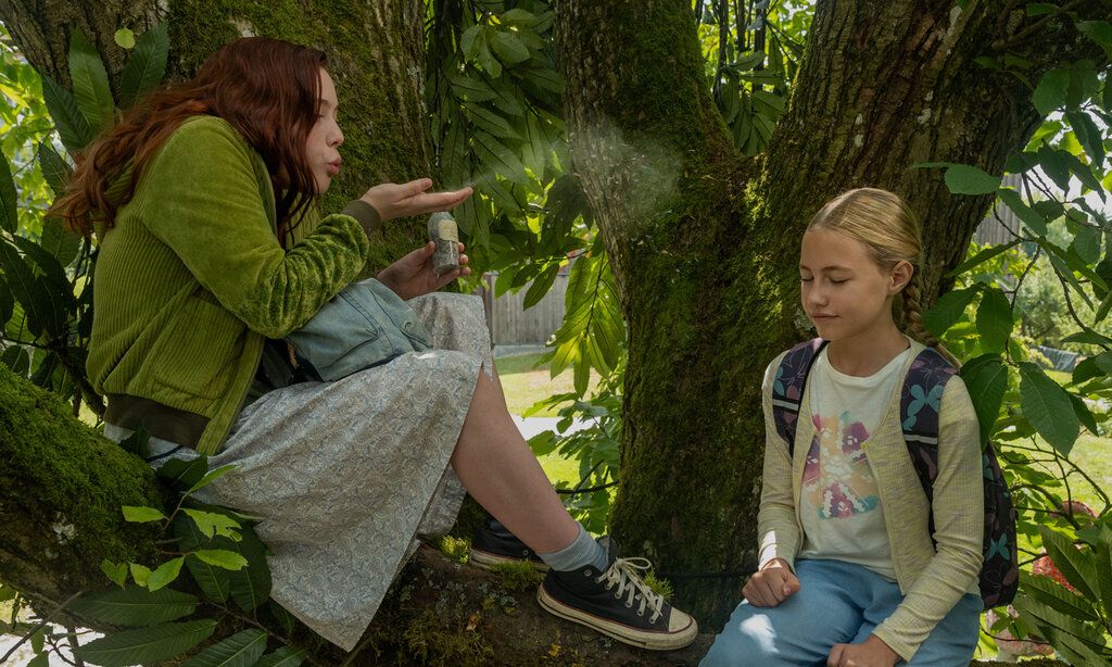 Szene aus dem Film Ein Mädchen namens Willow, zwei Mädchen sitzen auf einem Baum, das eine pustet etwas von seiner Hand zu dem anderen Mädchen