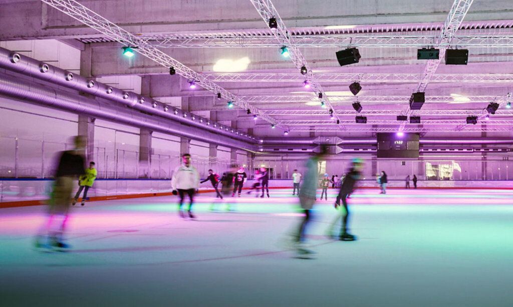 Innenraum der Eissporthalle Benrath, Schlittschuhläufer:innen mit Bewegungsunschärfe