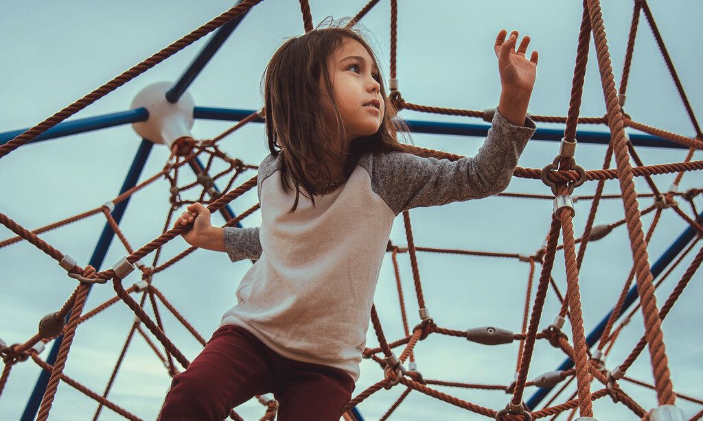 Mädchen klettert auf einem Seil-Klettergerüst herum