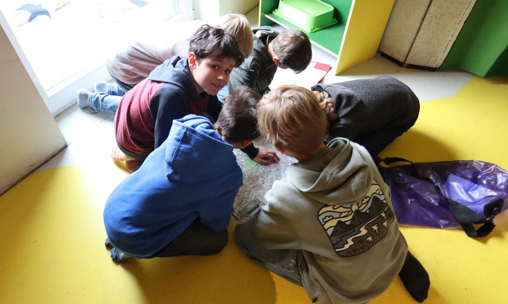 Sechs Jungs sitzen auf dem Boden und gucken sich eine Landkarte an