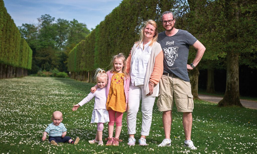 Vater, Mutter und zwei Kinder stehen wie die Orgelpfeifen im Benrather Schlosspark, ein Baby sitzt daneben im Gras