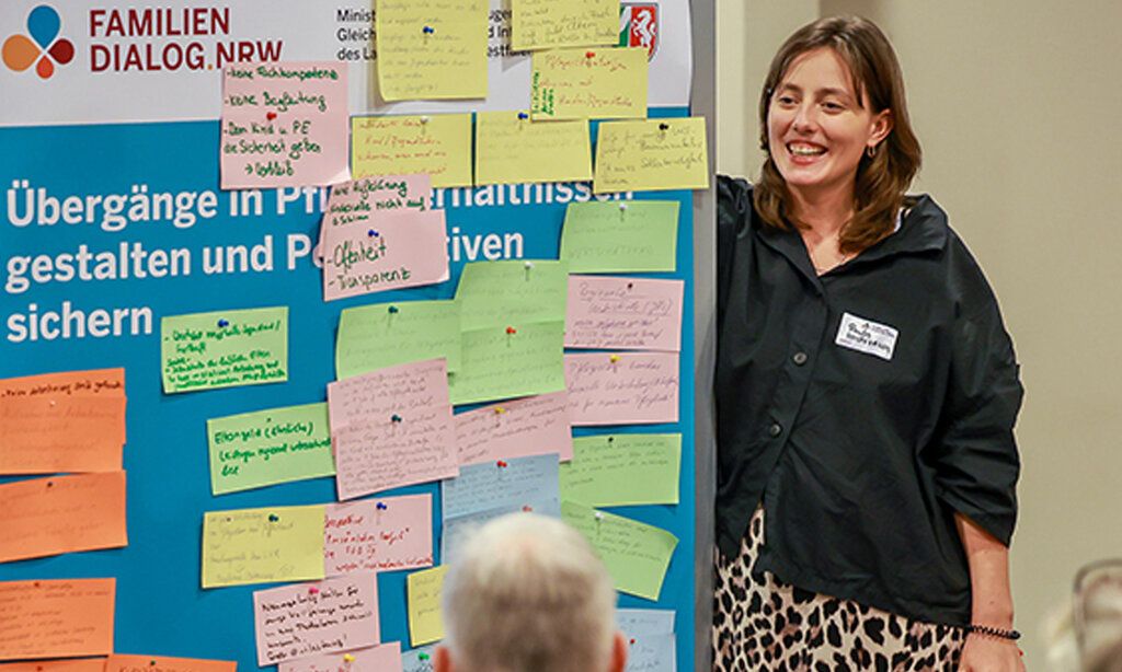 eine Frau steht an einem Stellwand, an der bunte Zettel hängen