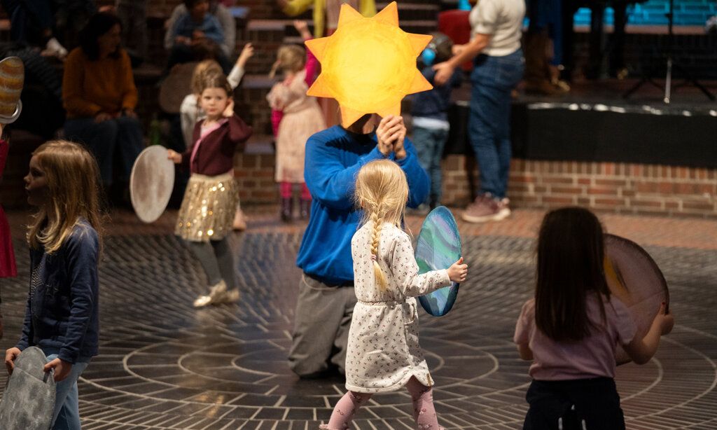 Familienmusikwoche Plutino, Kinder laufen herum, ein Mann kniet und hält einen Stern hoch