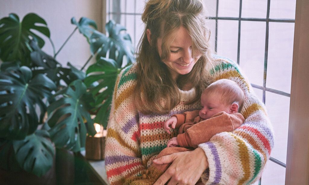 Porträt von Fee Fassbender mit Baby, im Hintergrund Zimmerpflanze