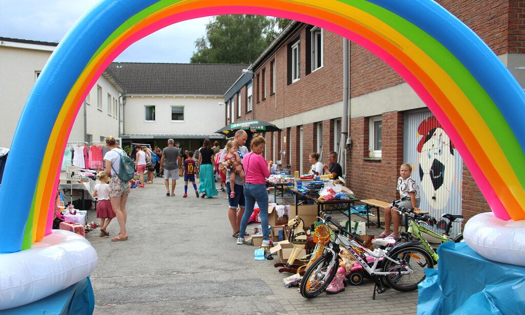 Trödelstände in Wohnsiedlung, im Vordergrund ein aufblasbarer Regenbogen