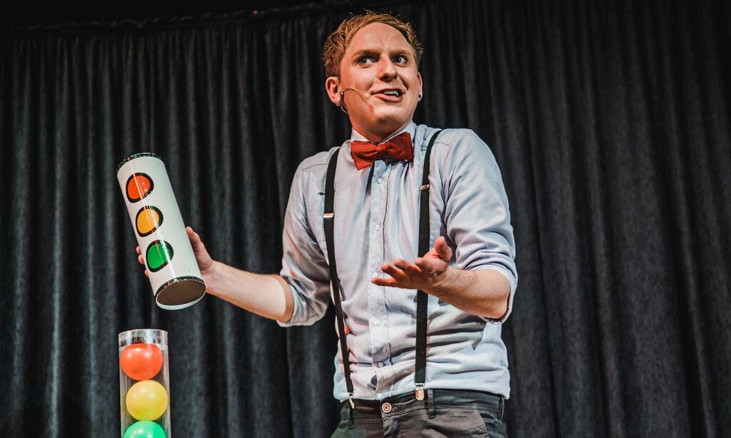 Zauberer Felix Wohlfahrt auf der Bühne, vor grauem Vorhang
