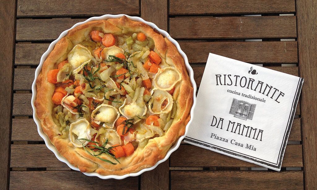 Fenchel-Karotten-Tarte von oben fotografiert mit einer Serviette, auf der steht: Ristorante da Mama, auf Holztisch