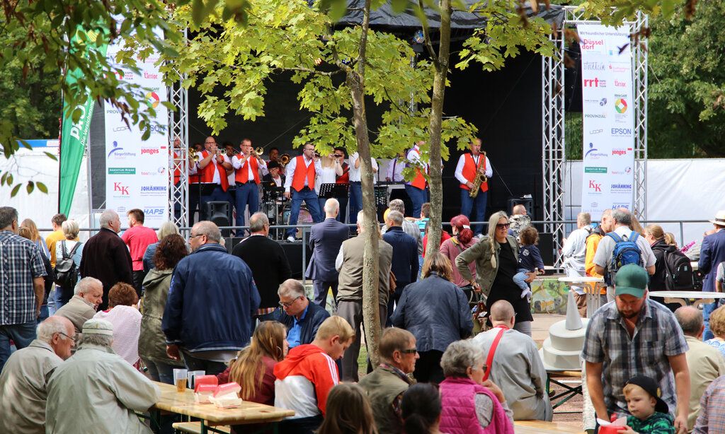 Menschen bei Open-Air-Veranstaltung, Musiker auf Bühne im Hintergrund