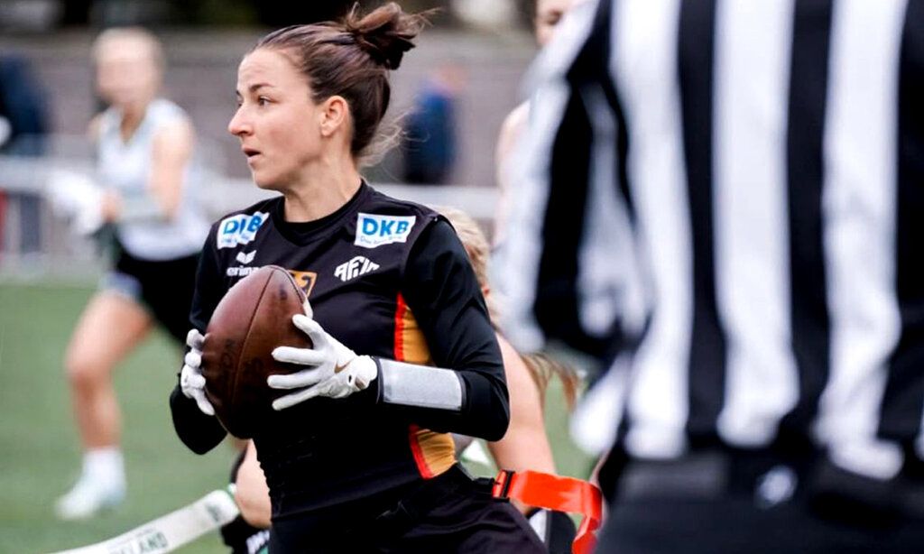 Flag Football Spielerin beim Spiel, im Vordergrund ein Schiedsrichter von hinten im gestreiften Shirt