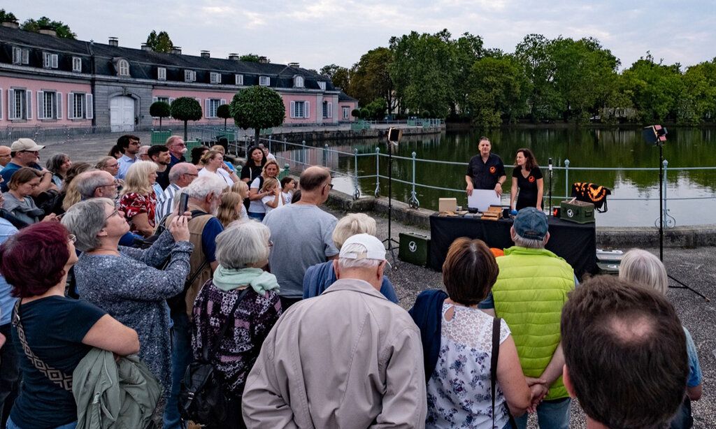 Guido Hoehne und Judith Funk sprechen vor dem Benrather Schloss über Fledermäuse, eine Gruppe von Leuten hört zu