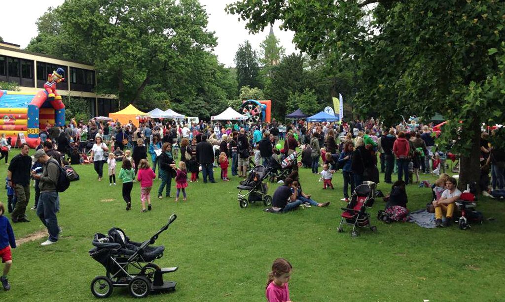 Wiese im Florapark mit vielen Menschen, Hüpfburg und Kinderwagen