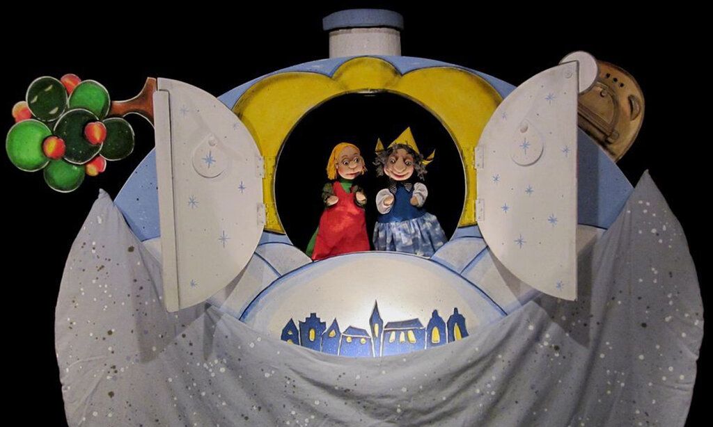 Frau Holle und die Marie gucken aus einer runden Öffnung in einer großen Kugel