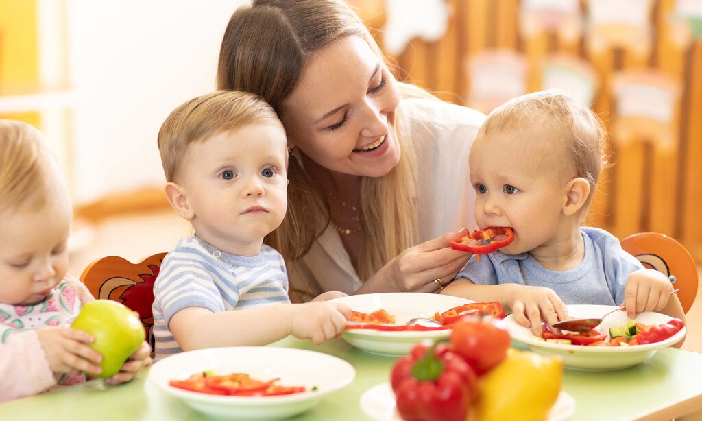 Frau mit Kleinkindern beim Essen