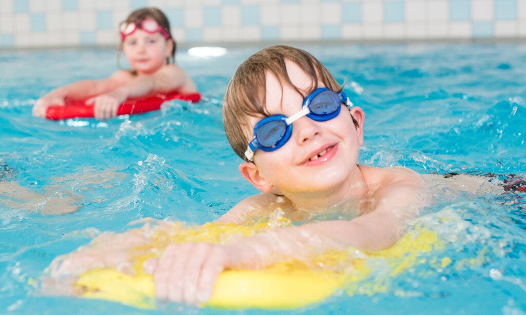 Kinder mit Schwimmbrettern in einem Schwimmbad