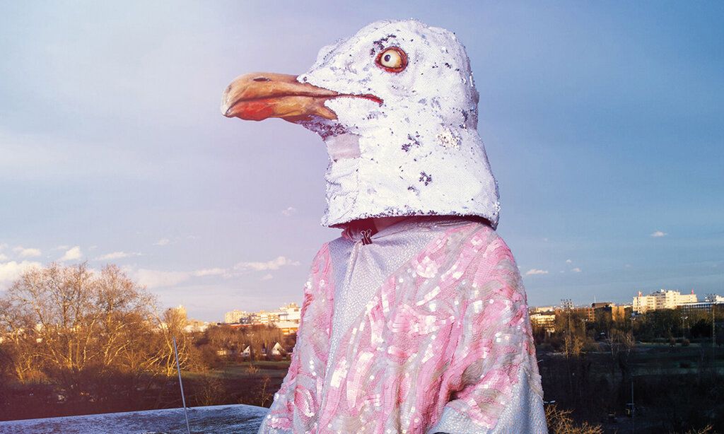 Schasuspieler mit Pinguinmaske, im Hintergrund Hochhäuser