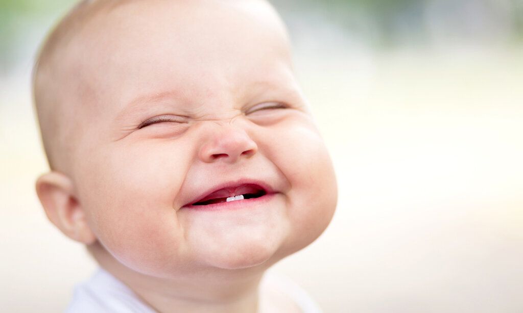Grinsendes Baby mit zwei Zähnen Unterkiefer