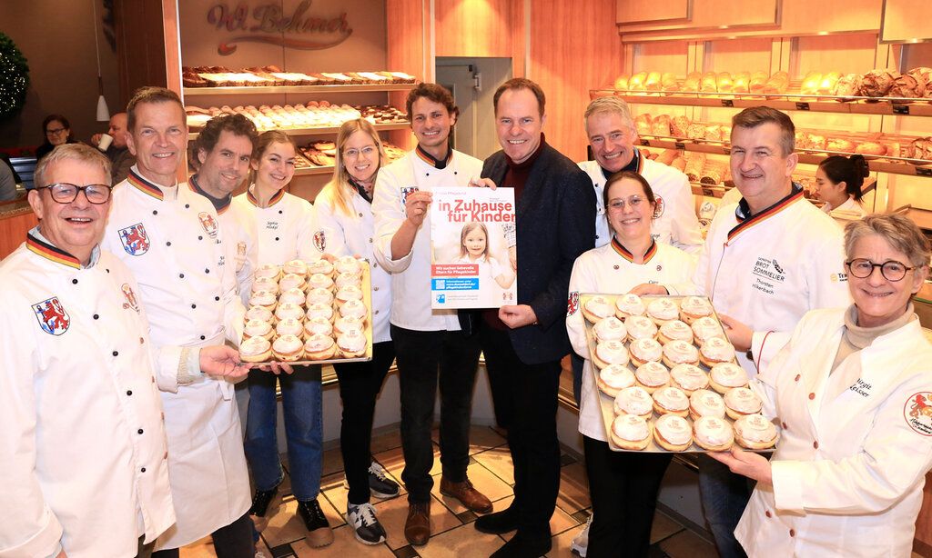 Handwerksbäcker stehen mit Backblechen voller Berliner in einem Verkaufsraum der Bäckerei Behmer