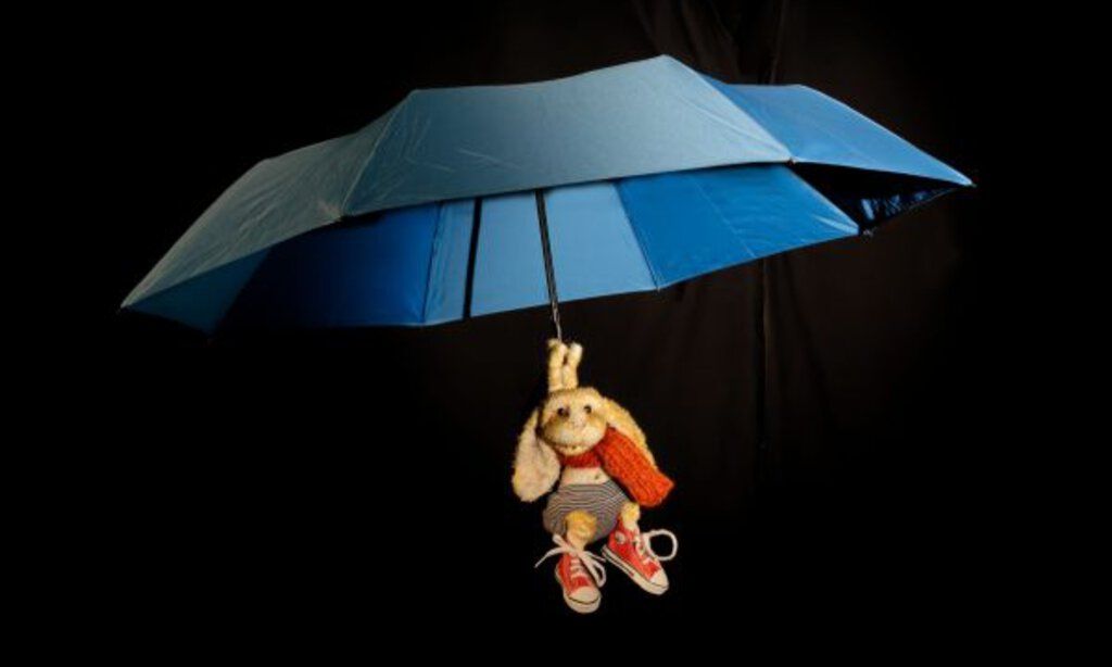 Eine Hasenpuppe schwebt an einem offenen Regenschirm