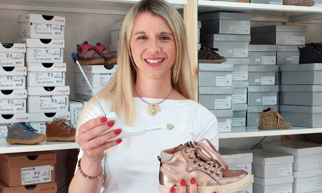 Stephanie Hammeley in ihrem schuhgeschäft, in der einen hand ein Fuß-Messgerät, in der anderen einen Kinderschuh
