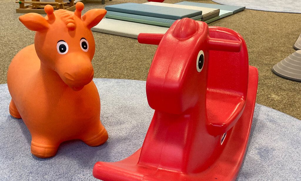 eine orange Hüpfkuh und ein rotes Schaukeltier, Indoorspielplatz Rheinkirche