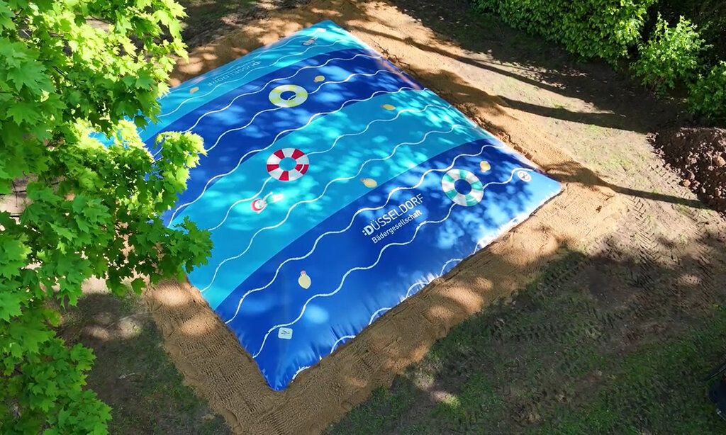 ein großes Hüpfkissen auf einer Wiese in einem Düsseldorfer Freibad