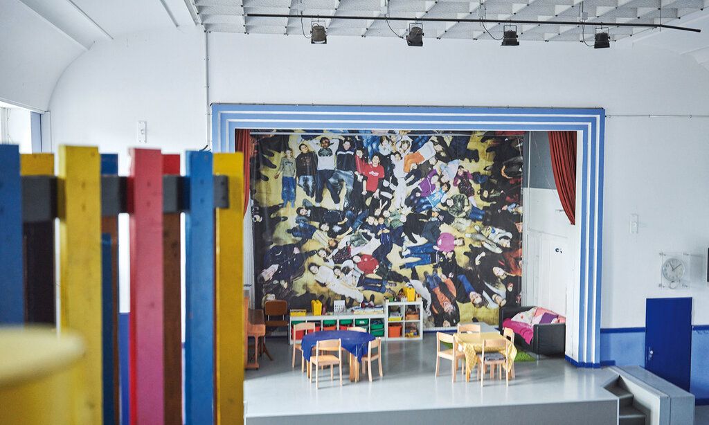 Innenraum des Kinderspielhauses, auf der Bühne stehen Tische und Stühle, menschenleer