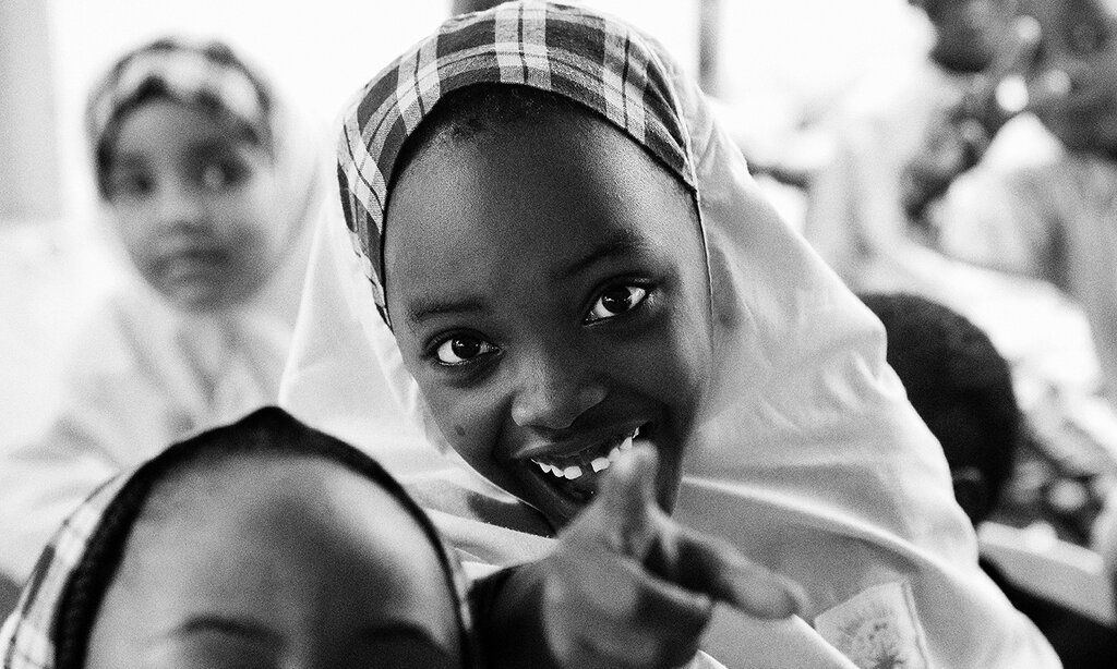 Mädchen schaut in die Kamera und zeigt mit dem Finger