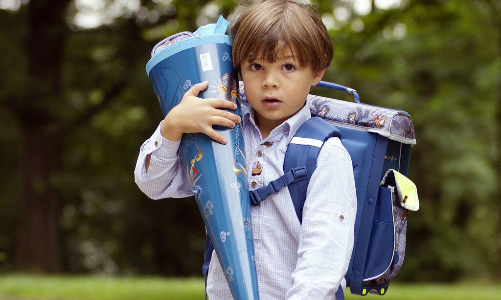 Junge mit blauer Schultüte im Park
