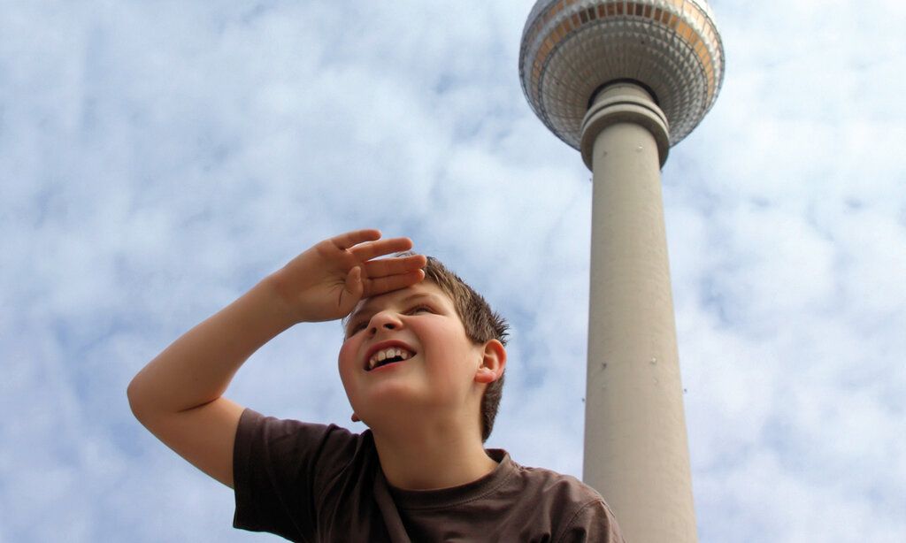 Junge steht vor Berliner Fernsehturm und guckt in die Ferne