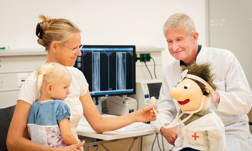 Mutter mit Kind im Arztgespräch, eine Arztpuppe ist auch dabei