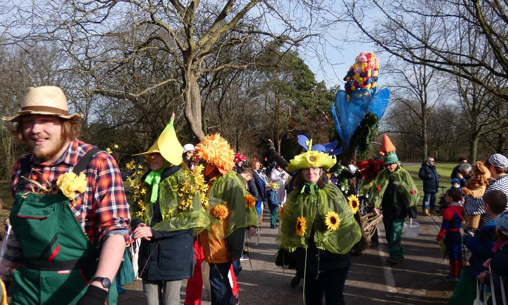 Als Bauern und Blumen verkleidete Leute ziehen durch den Südpark