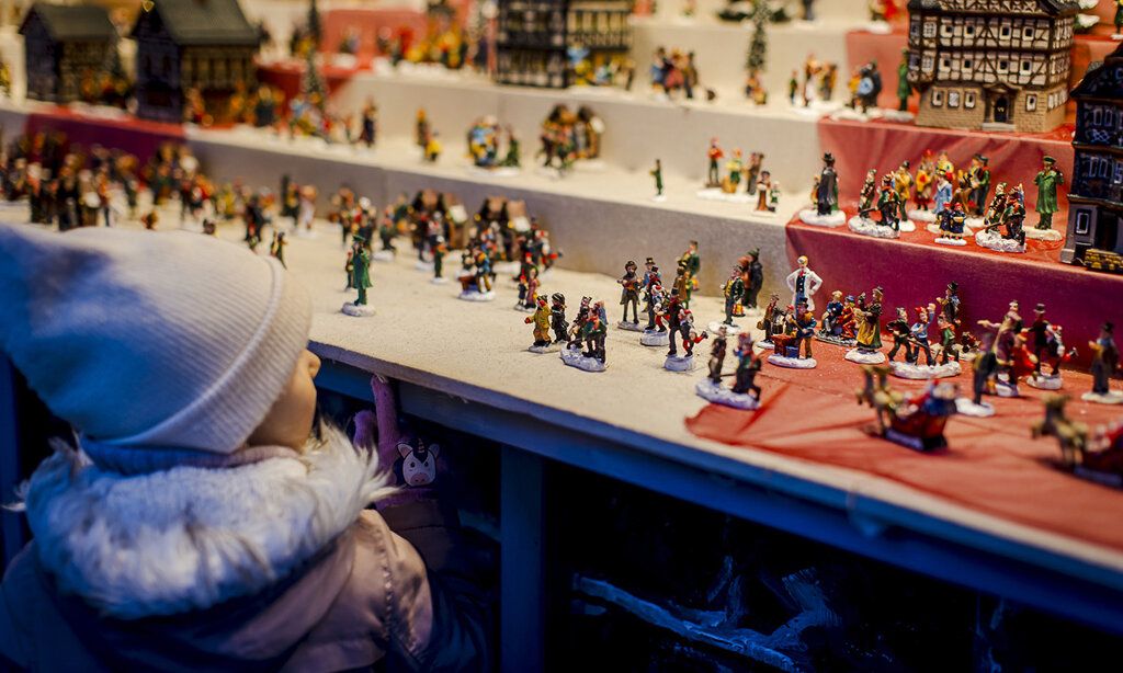 ein Kind steht an einem Weihnachtsmarktstand und guckt sich kleine Zinnfiguren an