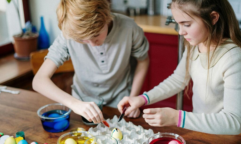 ein Junge und ein Mädchen färben Ostereier