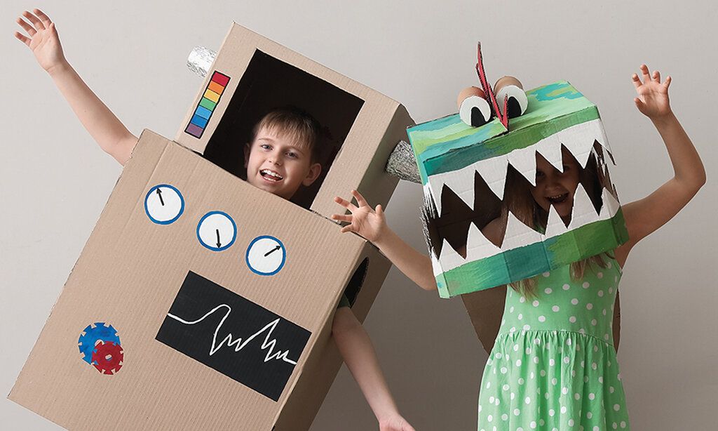 Kinder mit Kostümen aus Pappkartons: Junge als Roboter, Mädchen als Krokodil verkleidet