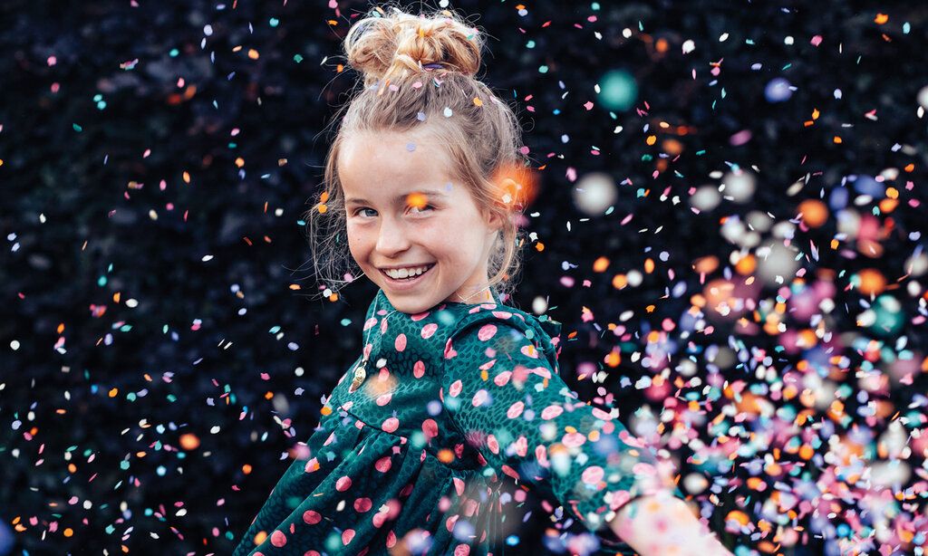Mädchen im Konfettiregen, lacht, Hintergrund dunkel