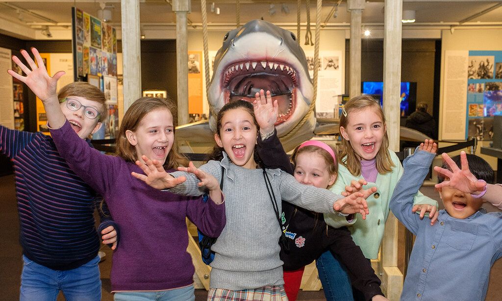 Gruppenbild von Kindern bei der Kindermuseumsnacht im Filmmuseum vor einer Hai-Attrappe