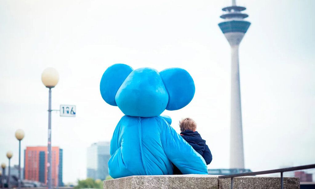 Blauer Elefant, Maskottchen des Kinderschutztbund sitzt mit kleinem Jungen vor dem Rheinturm