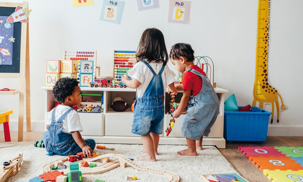 Drei Kleinkinder spielen in einem Kinderzimmer