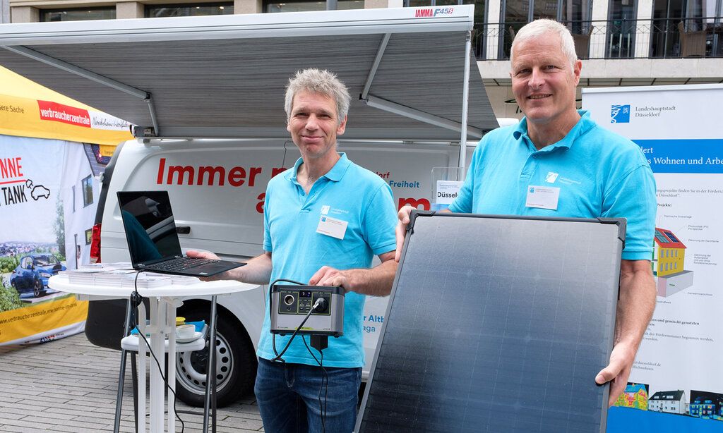 Zwei Männer stehen vor dem Klimamobil und präsentieren eine Solarenergieanlage