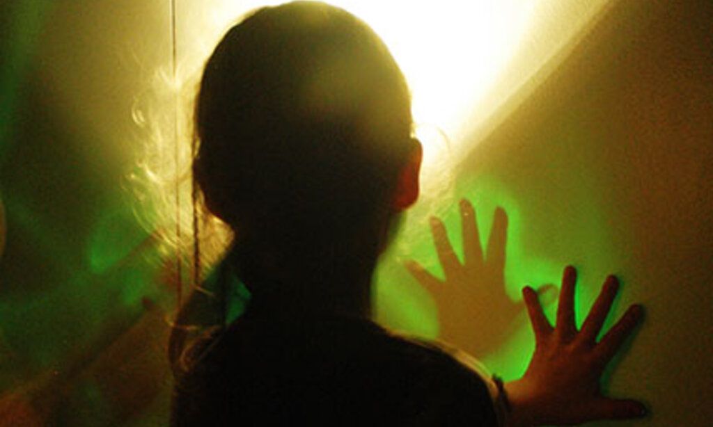 Ein Mädchen legt ihre Hände auf eine Wand mit bunten Lichtinstallationen