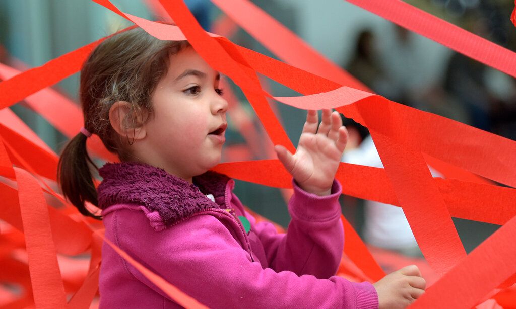 Ein Mädchen ist umgeben von roten Bändern