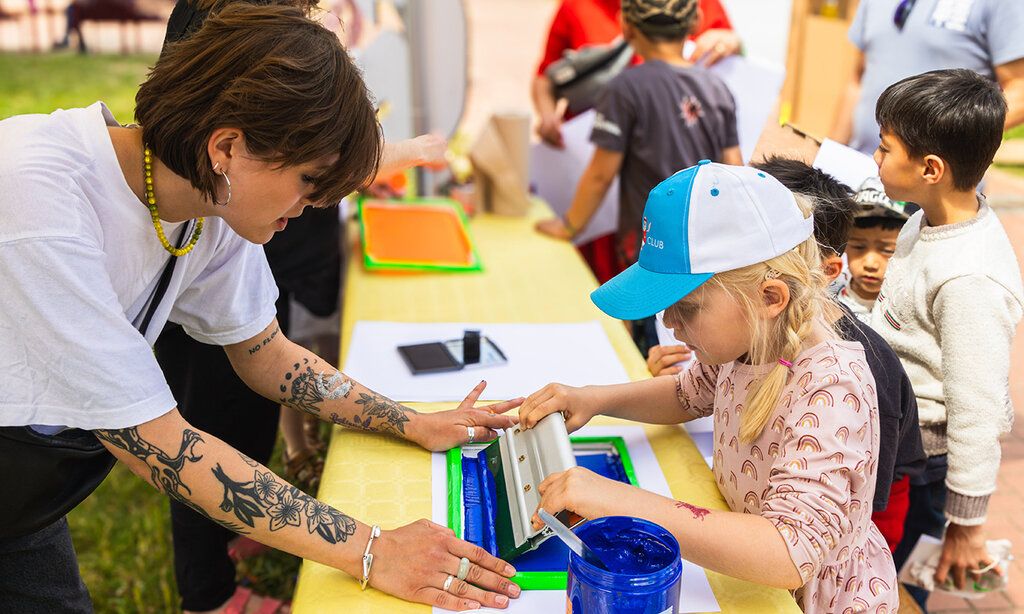 Mädchen macht Siebdruck an einem Stand beim Mitmachfestival Konferenz der Kinder