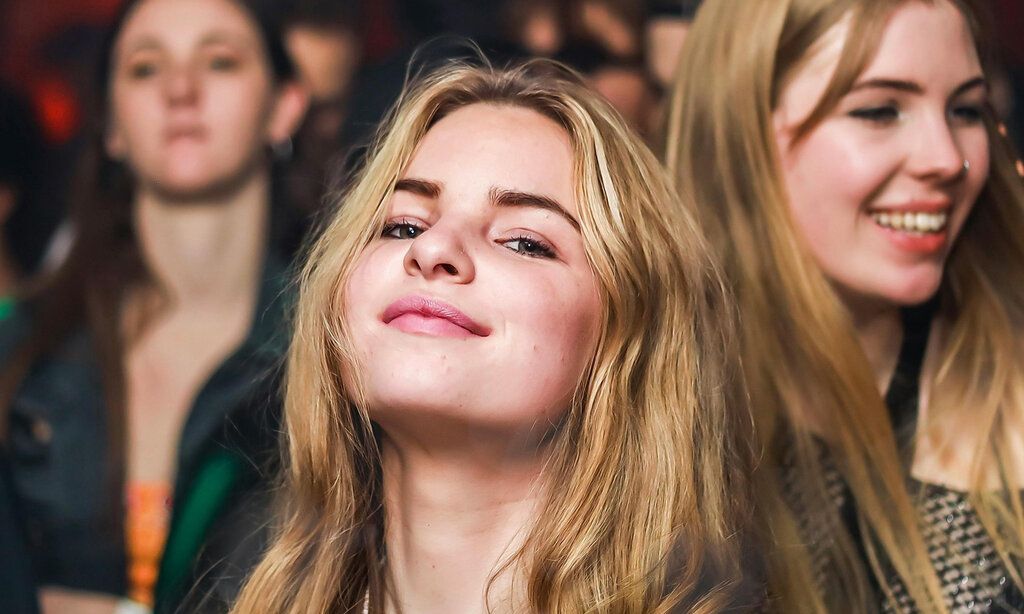 Teenie-Mädchen guckt selbstbewusst in die Kamera, im Hintergrund andere Mädchen